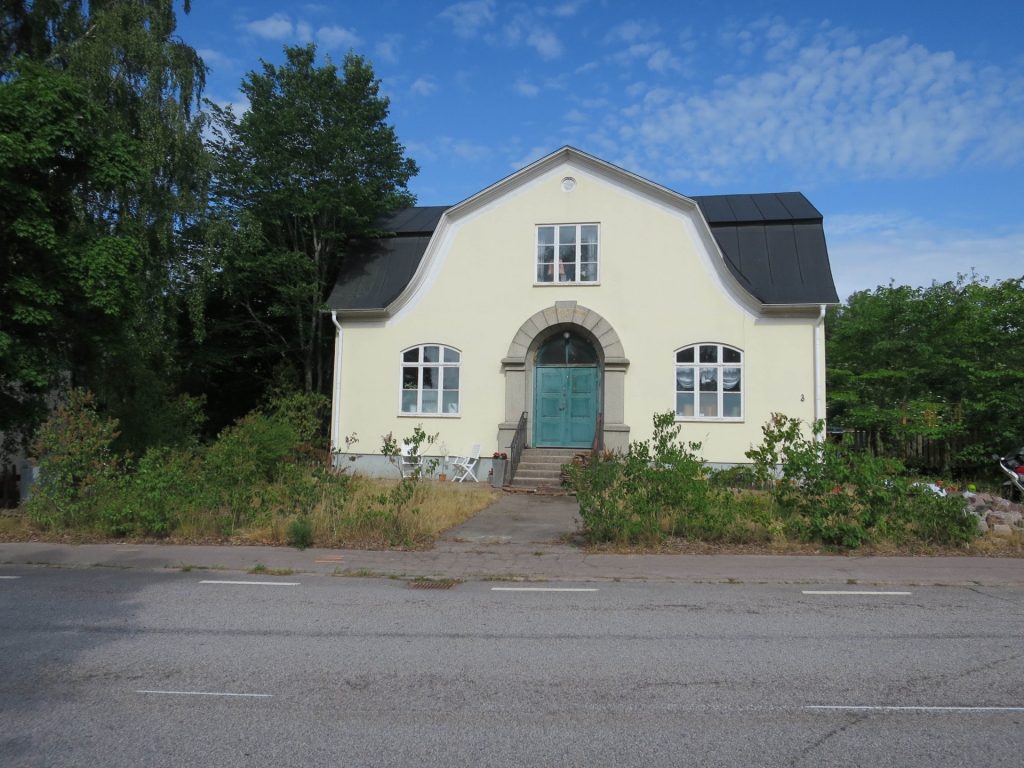 Ett gult hus med svart tak och grön dörr.